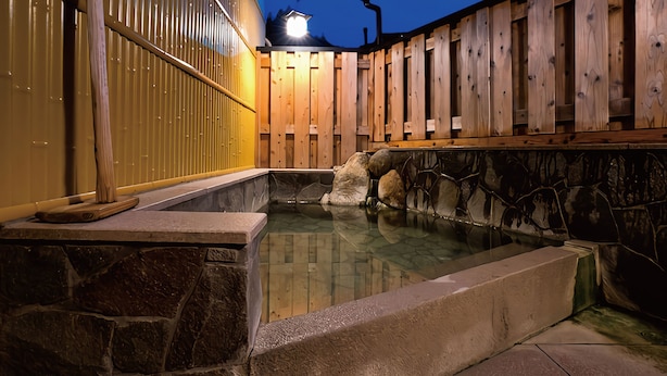 Een traditioneel Japans onsen met stenen muren en houten leuningen.