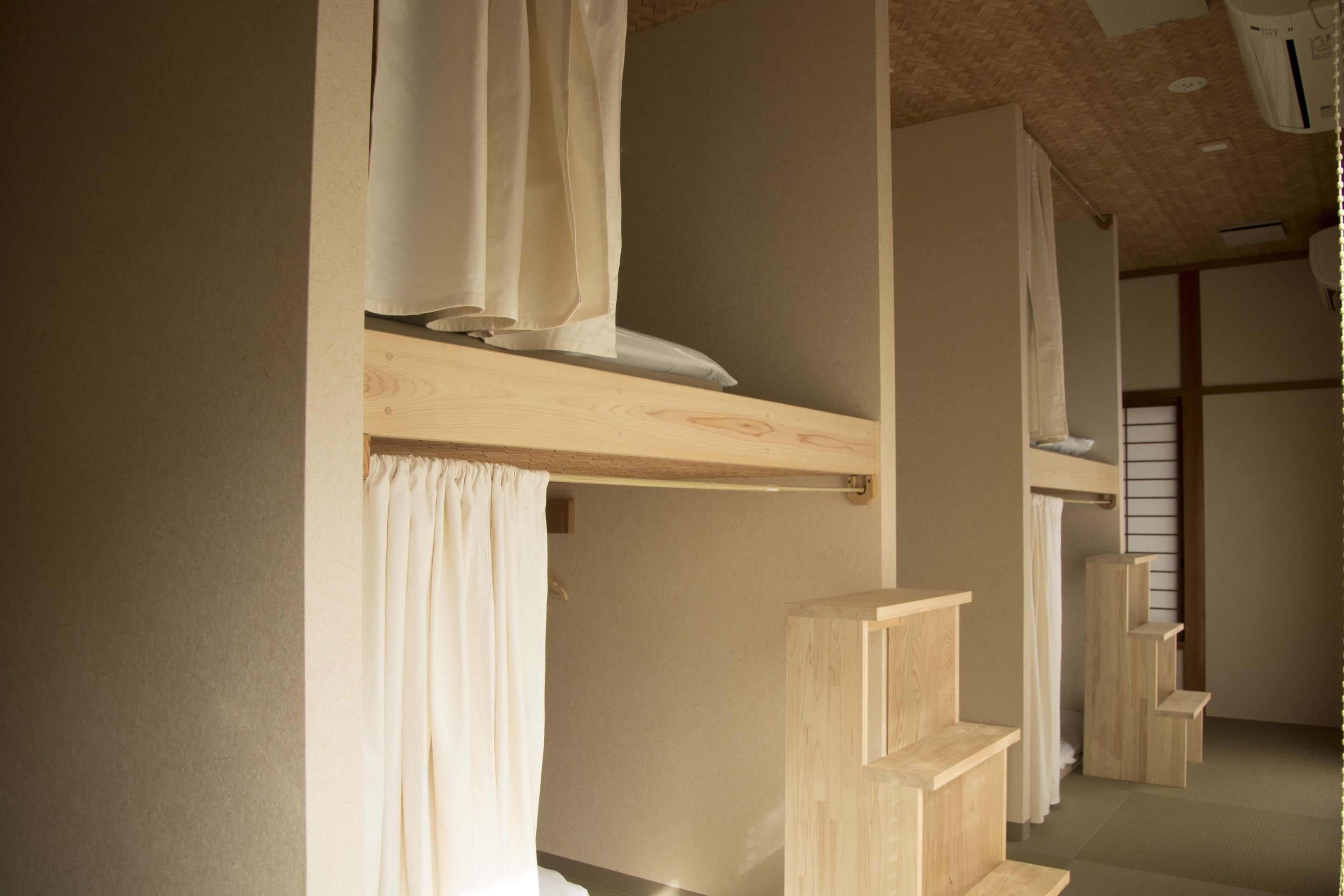 Una habitación con una cama litera de madera, una cortina y una estantería.