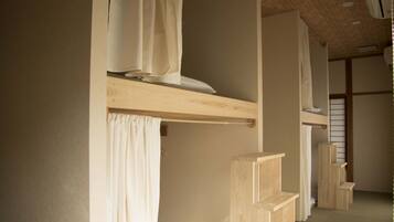 A room with a wooden bunk bed, a curtain, and a shelf.