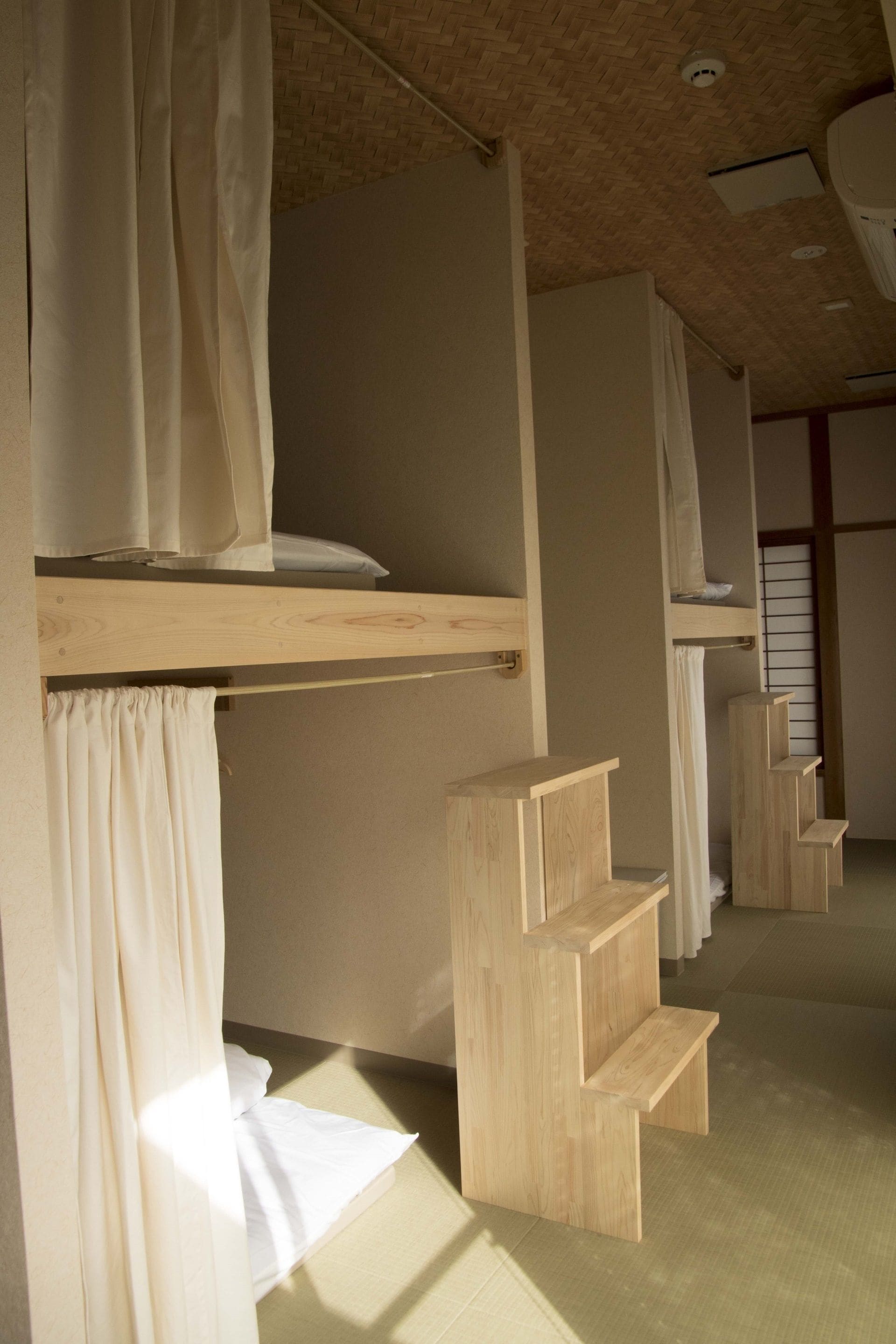 Una habitación con literas, estanterías de madera y suelo de tatami.
