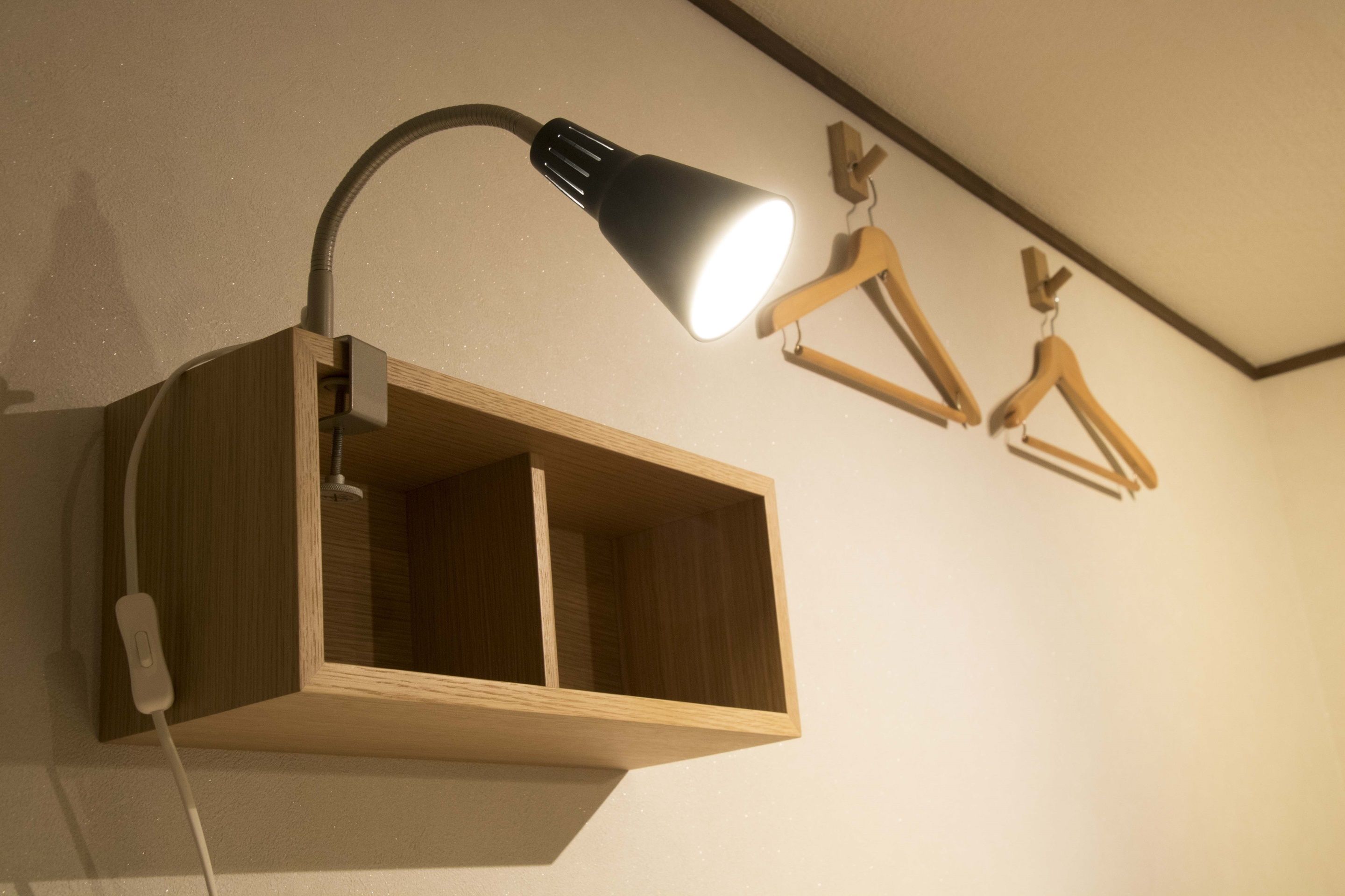A wall-mounted wooden cabinet with a desk lamp and a power strip.