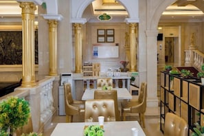 Un comedor con una mesa blanca, sillas doradas y una columna central.