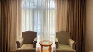 A room with two armchairs, a small round table, and sheer curtains. - Vienna International Hotel （Longgang Universiade Center Subway Station） (Shenzhen)
