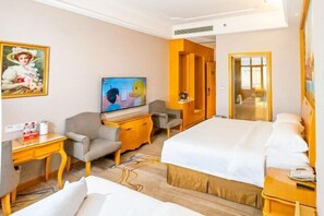 Una habitación de hotel con cama, escritorio, silla, televisor y puerta que da a otra habitación.