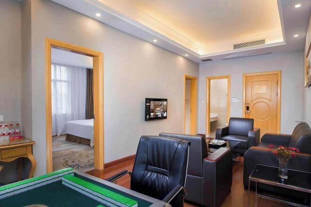 Habitación de hotel con cama, escritorio, mesa de billar y una zona de estar con sillas y sofás.