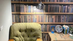 A room with a green armchair, a wooden side table, a floor lamp, and a bookshelf filled with books. - Good Farming Day B&B (Chishang)