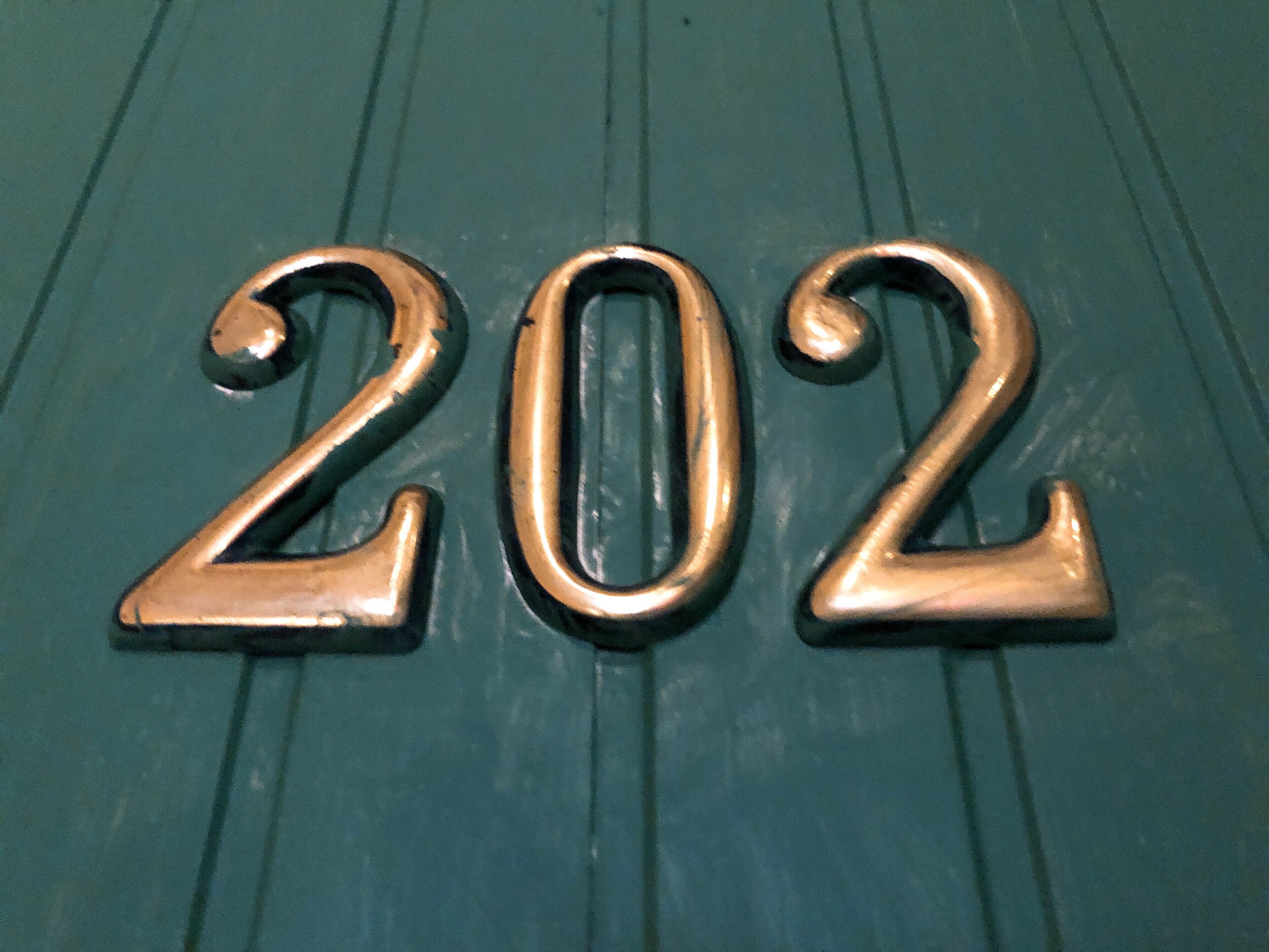 A metallic number "202" on a textured surface.