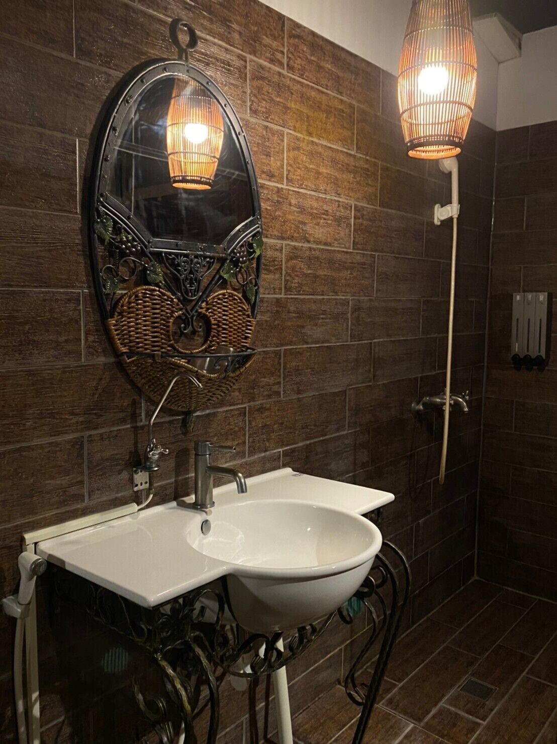 Un baño con lavamanos blanco, espejo con marco decorativo y cabina de ducha.