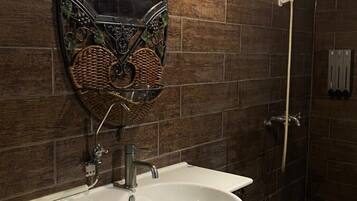 Un baño con lavamanos blanco, espejo con marco decorativo y cabina de ducha.
