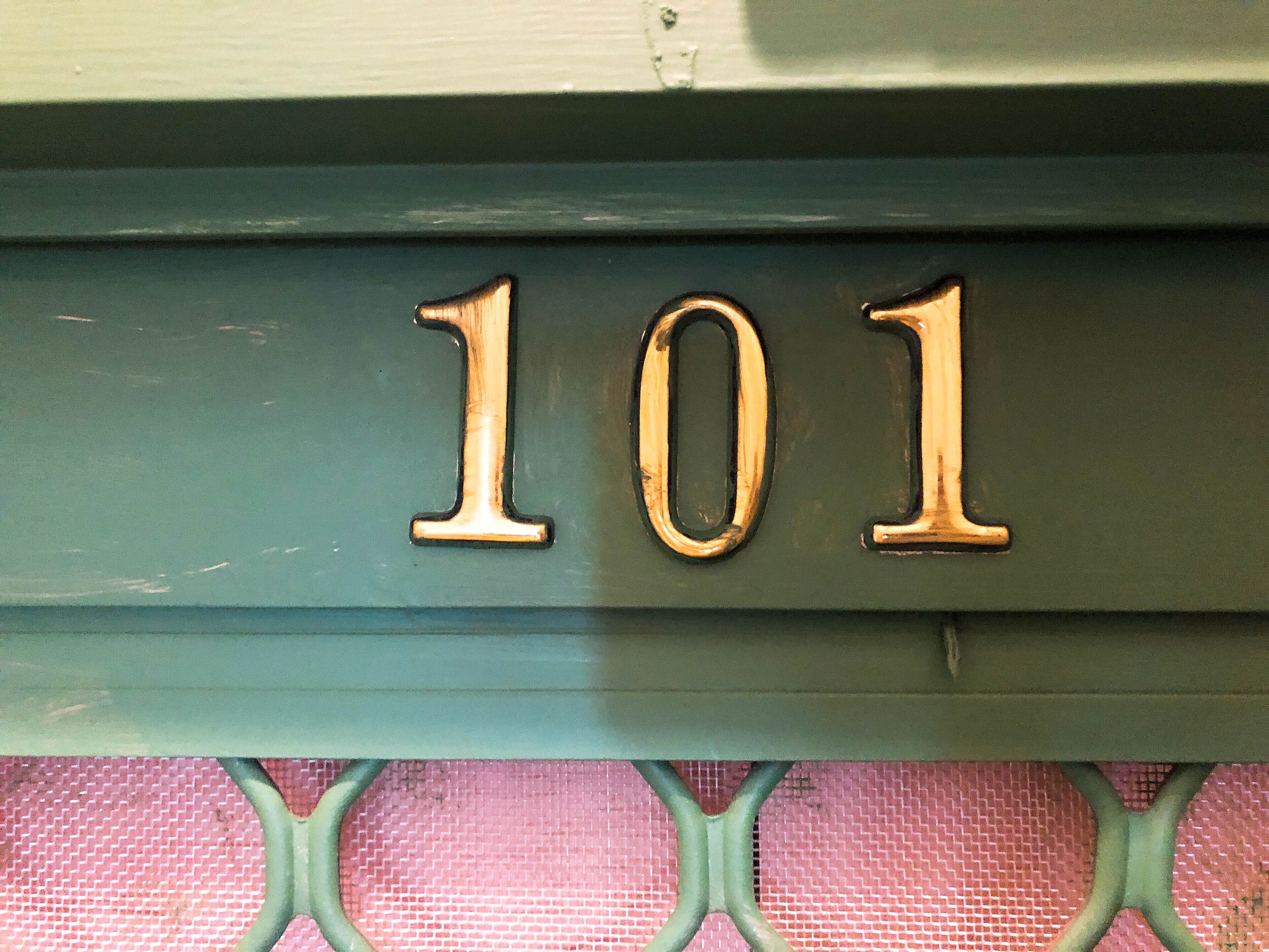 A close-up of a building number '101' on a green metal structure.