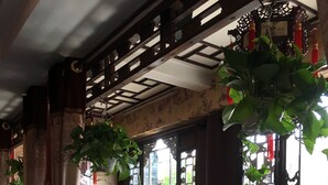 A traditional interior with wooden furniture, a decorative door, and potted plants. - Pingyao Yuchengyuan Hotel (Jinzhong)