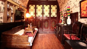 A traditional room with a wooden bed, a desk with a chair, a television, and a decorative door with intricate designs. - Pingyao Yuchengyuan Hotel (Jinzhong)