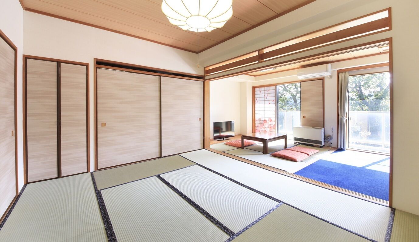 A traditional Japanese room with tatami flooring, sliding doors, and a view of the outdoors.