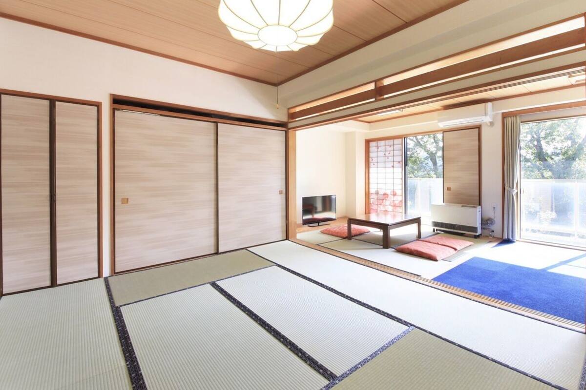 A traditional Japanese room with tatami flooring, sliding doors, and a view of the outdoors.