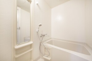 Et hvidt badeværelse med badekar, brusebad og spejl.