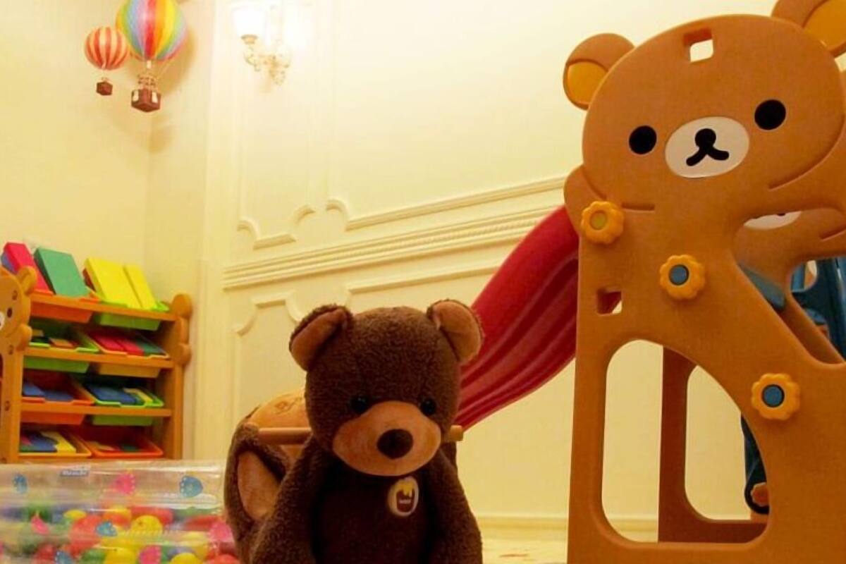 A room with a play area including a teddy bear and a toy chair.