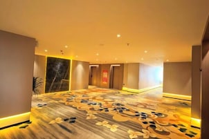 A hotel corridor with a patterned carpet, doors, and recessed lighting.