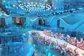 Un espace intérieur spacieux, doté de tables et de chaises rondes, d’une composition florale centrale et d’un design moderne au niveau du plafond.
