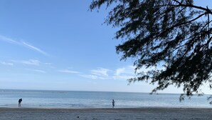 A beach with large rocks in the foreground and a clear view of the sea.