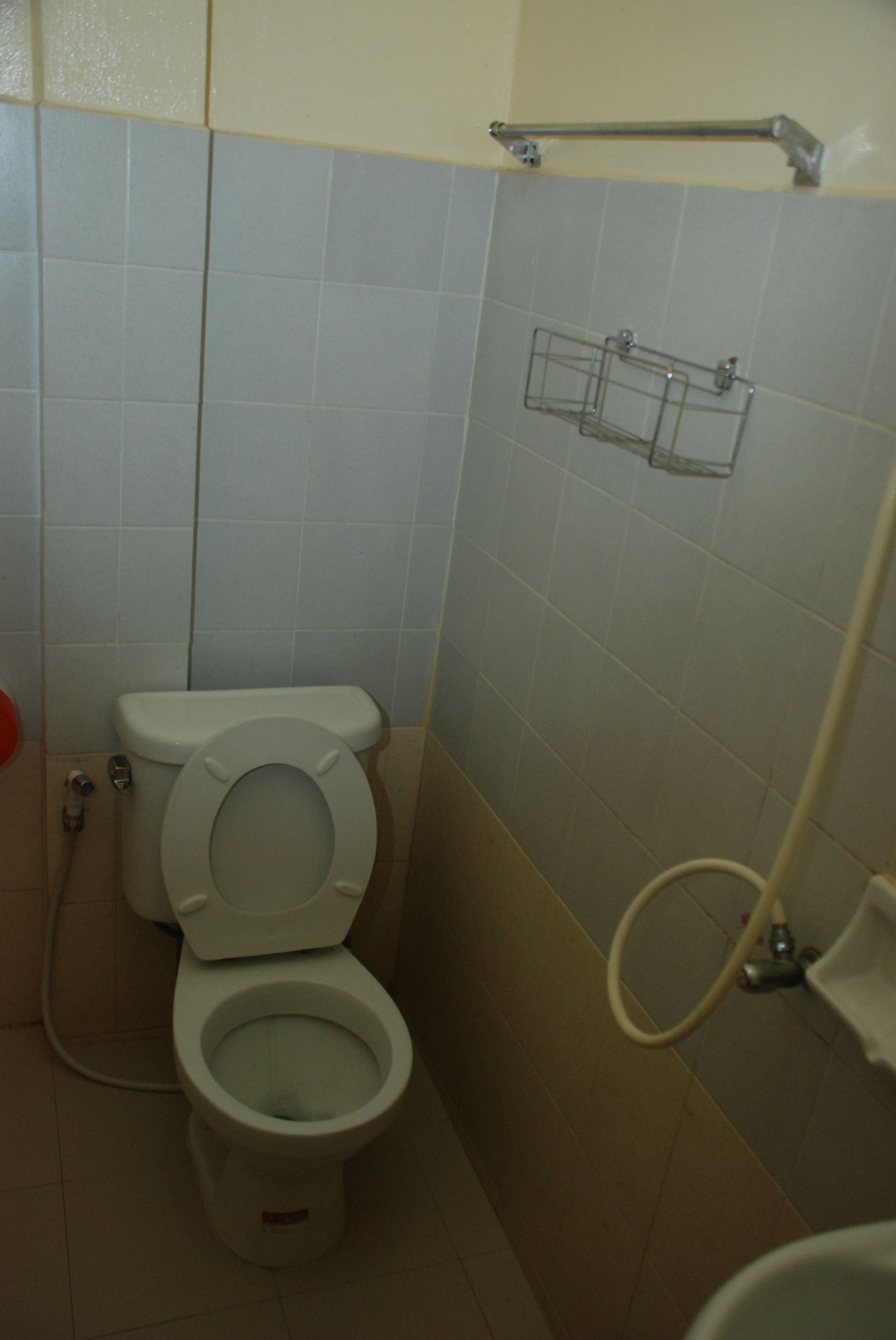 A small bathroom with a toilet, a hand dryer, and a towel rack.