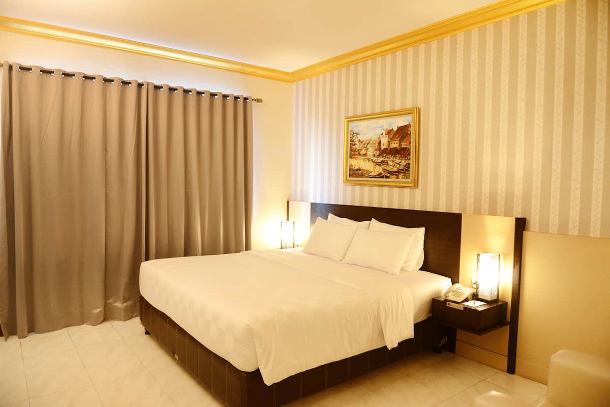 Ein Hotelzimmer mit einem großen Bett, einem Nachttisch mit Lampe und einem Gemälde an der Wand.