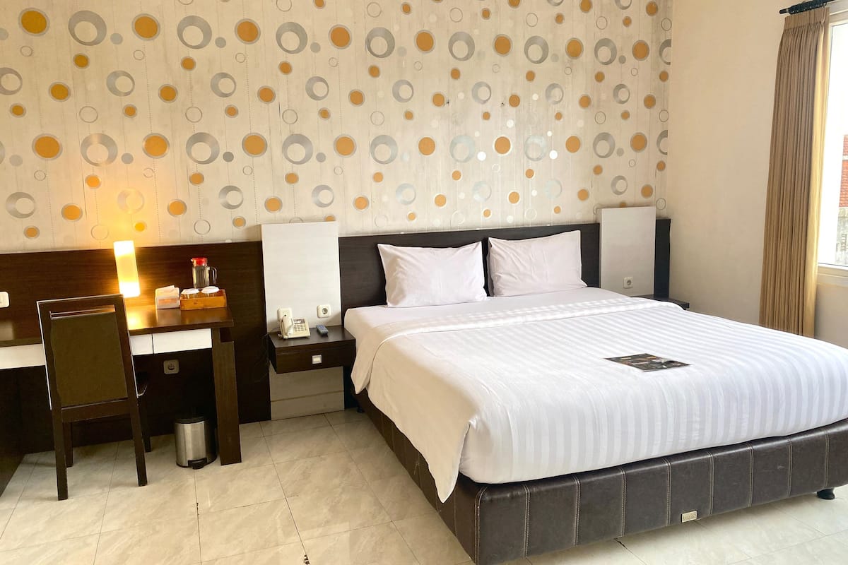 Ein Hotelzimmer mit Bett, Nachttischen, einem Schreibtisch und einem Sessel.