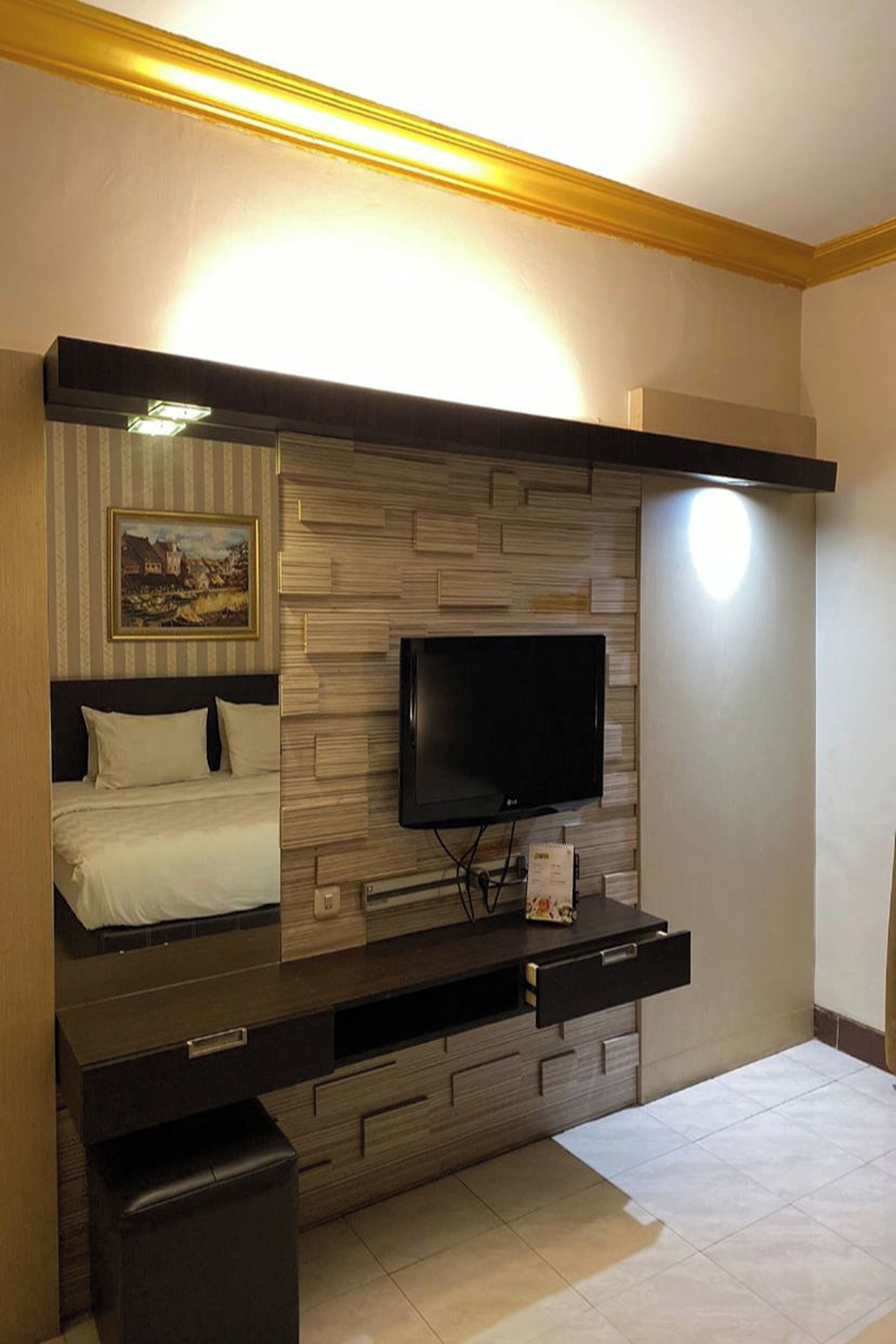 A modern bedroom with a bed, a flat-screen TV mounted on a wooden wall, and a small bedside table.