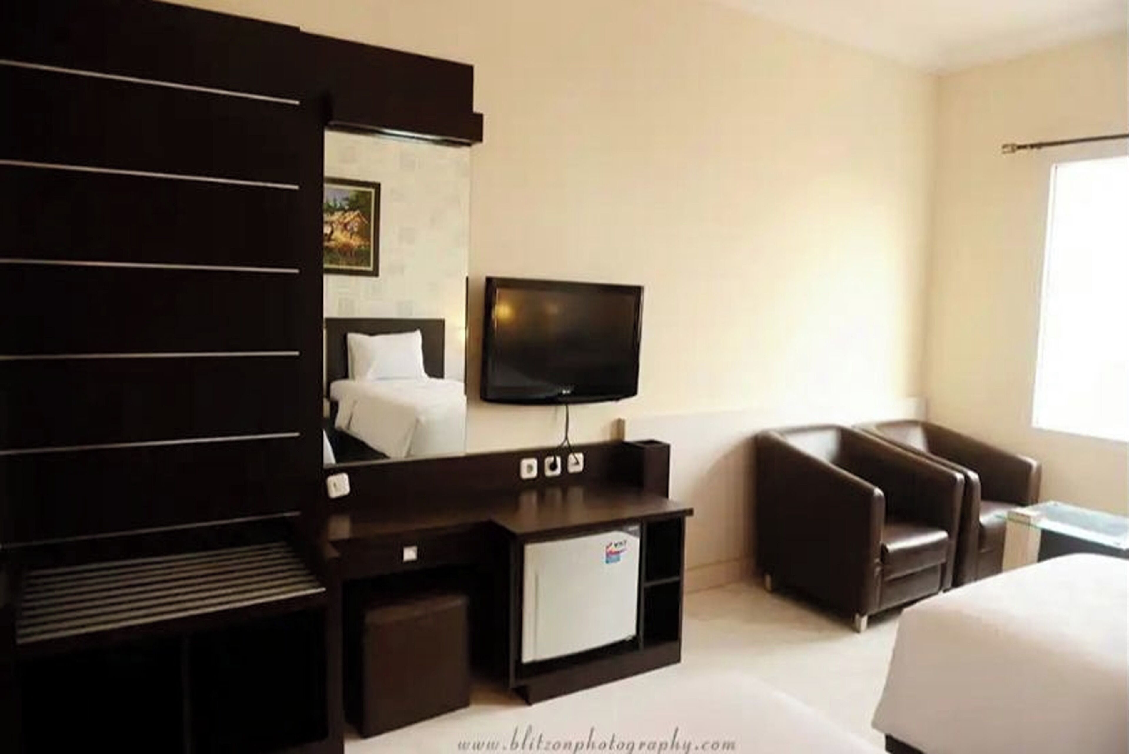 Habitación de hotel con cama, televisión, escritorio y zona de estar.