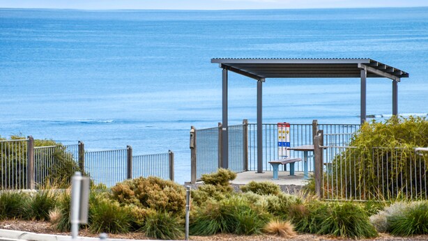 A coastal walkway with a metal pergola, benches, and a fence. - Bayside (Aldinga Beach)