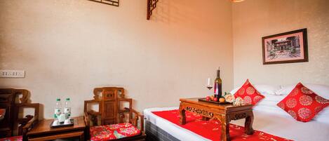 A hotel room with a bed, a wooden nightstand, a chair, a table, and a wall-mounted air conditioner.