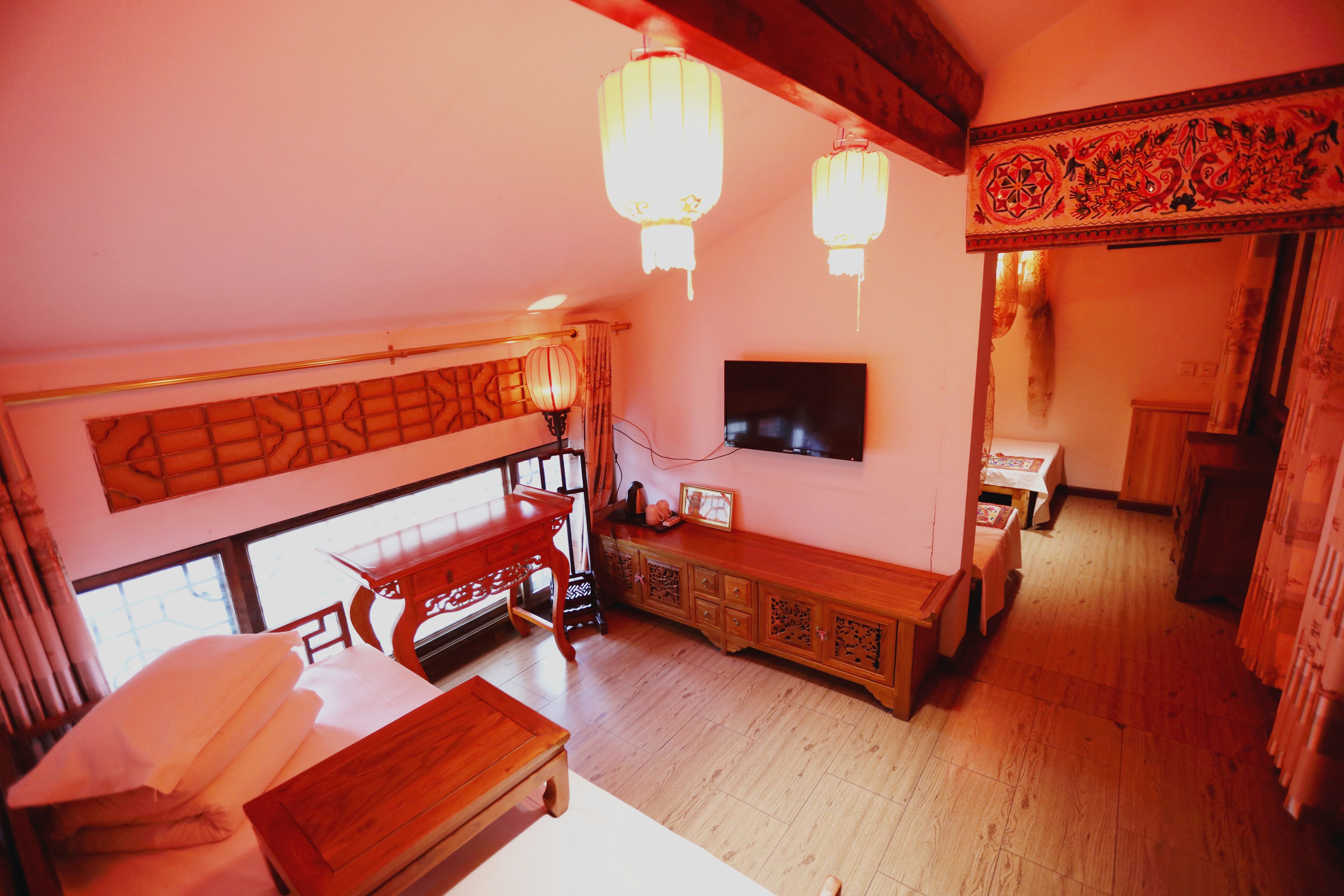 A traditional room with a bed, wooden furniture, a TV, and decorative elements.