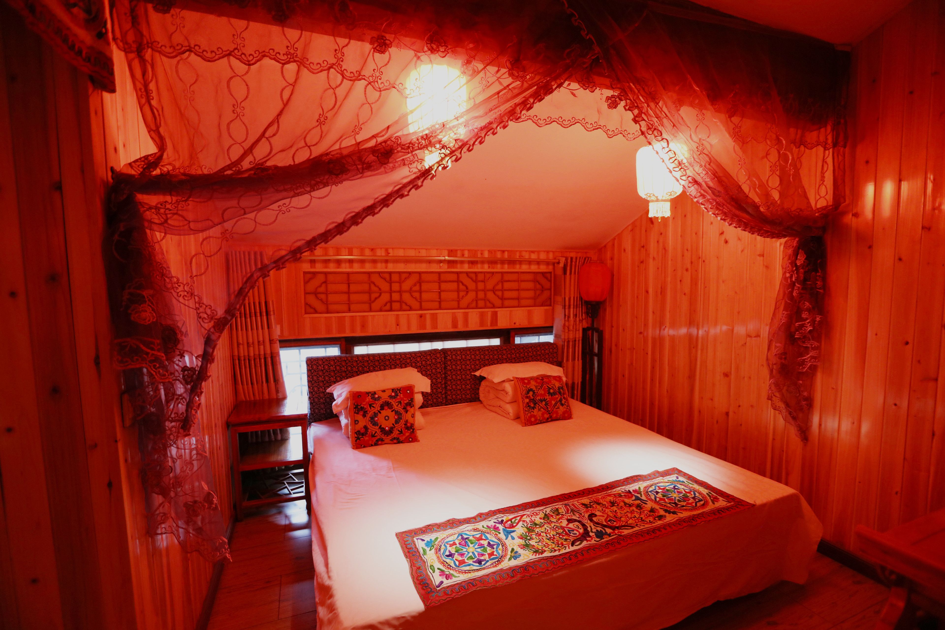 A room with a bed, a nightstand, and a window with curtains.