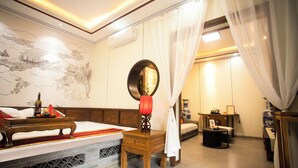 Una habitación tradicional con una cama, mesita de noche y una pequeña mesa con lámpara.