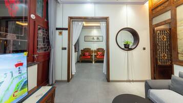 Un salón de estilo tradicional con televisor, sofá y una puerta de madera con diseños intrincados.