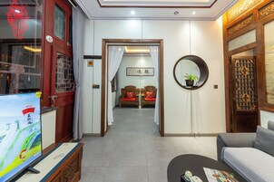 Un salón de estilo tradicional con televisor, sofá y una puerta de madera con diseños intrincados.