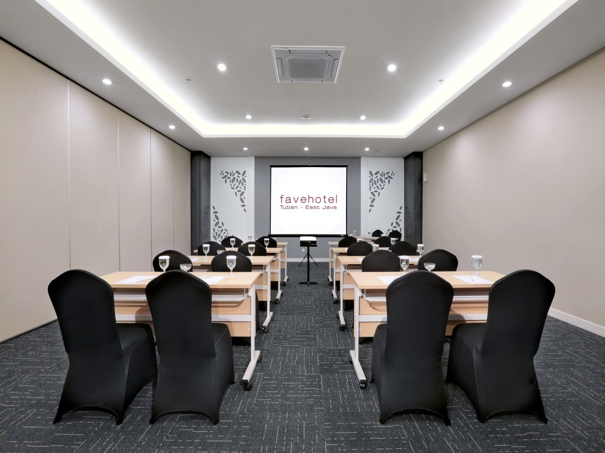 Een vergaderzaal met een projectorscherm waarop 'favehotel Tuban - East Java' staat.