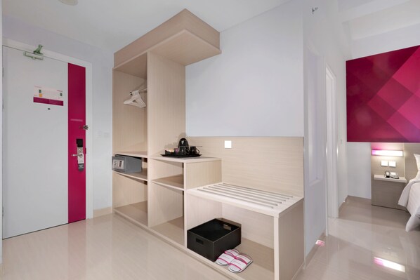 Una habitación de hotel moderna con cama, escritorio, silla, una mesita y un armario.