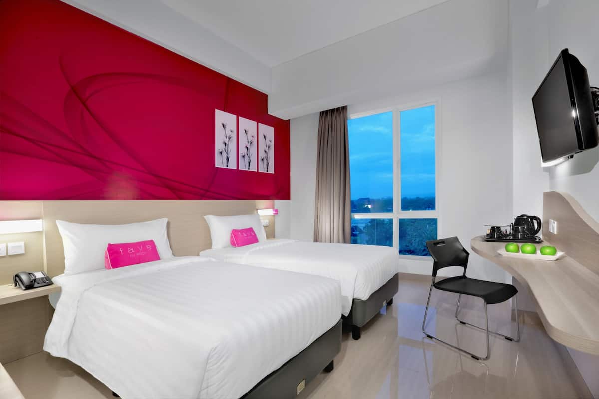 A hotel room with two beds, a TV, a desk with a chair, and a window with a view.