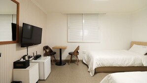 Ein Hotelzimmer mit Bett, Fernseher, Schreibtisch und Stuhl.