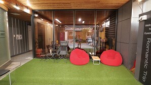 Ein modernes Interieur mit einem grünen Kunstturfteppich, zwei roten Sitzsäcken, einem Klappsessel und einem kleinen Tisch.