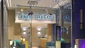 A hotel entrance with a glass door, a reception desk, and a seating area with a sofa and chairs. - Aley Suites (Aley)