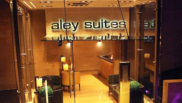 A hotel entrance with a reception desk, seating area, and a sign reading "alley suites". - Aley Suites (Aley)