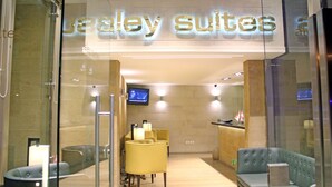 A hotel lobby with a reception desk, seating area, and a TV screen. - Aley Suites (Aley)