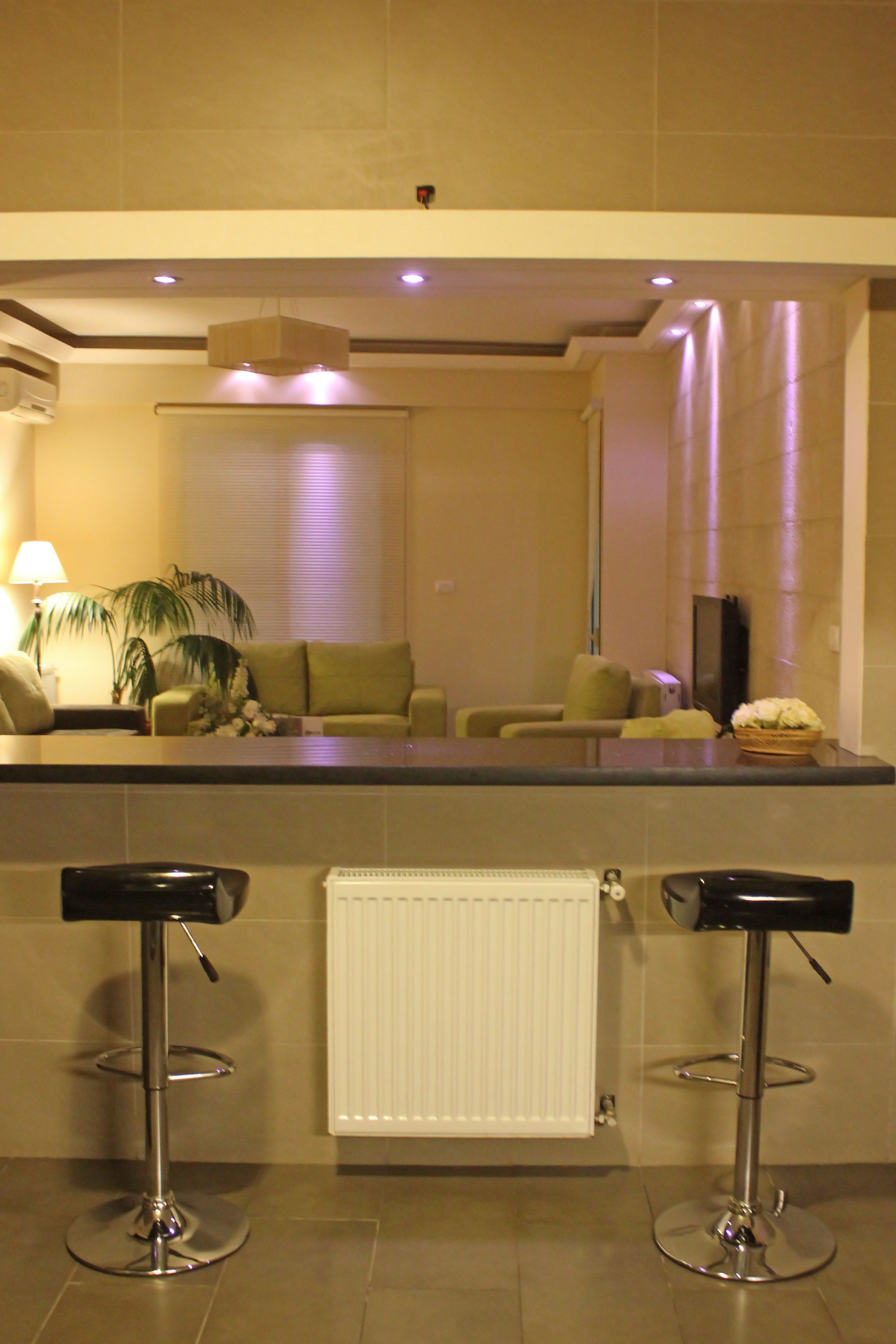 A modern living area with a sofa, two bar stools, a lamp, and a plant.