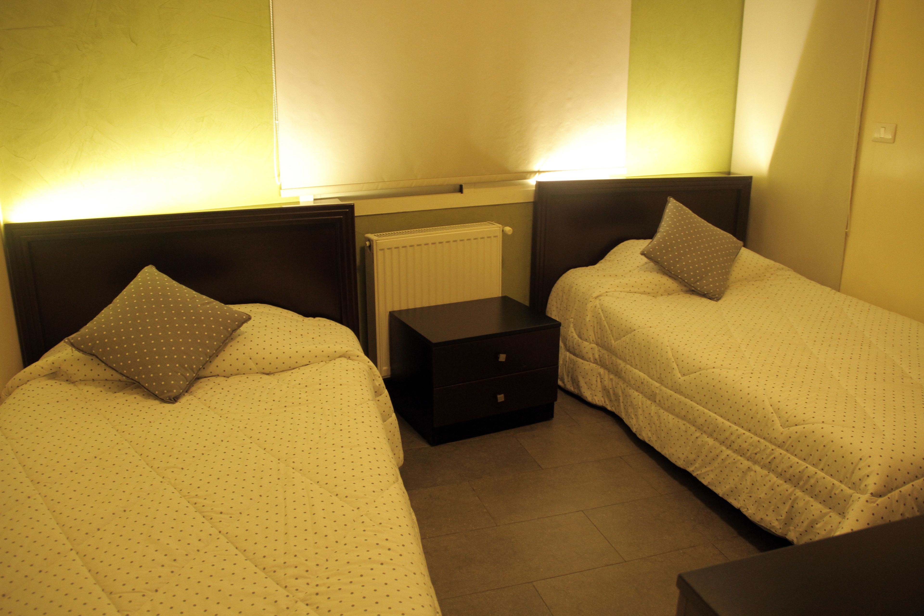 A twin room with two beds, a nightstand, and a radiator.