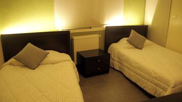 A twin room with two beds, a nightstand, and a radiator.