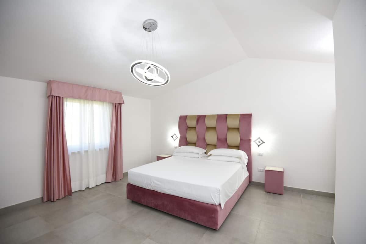 A modern bedroom with a large bed, a headboard with vertical stripes, and a bedside table.