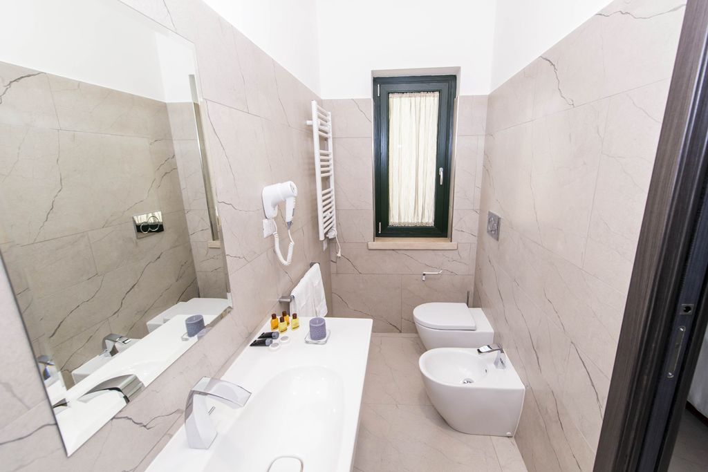 Une salle de bain moderne avec un grand miroir, un lavabo blanc, un bidet et des toilettes.