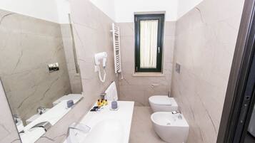 Une salle de bain moderne avec un grand miroir, un lavabo blanc, un bidet et des toilettes.