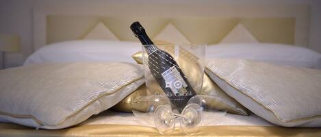 A bed with a bottle of wine and a glass on it.